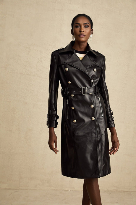 A black leather coat with doublebreasted front closure and belt worn by a model standing against a plain background