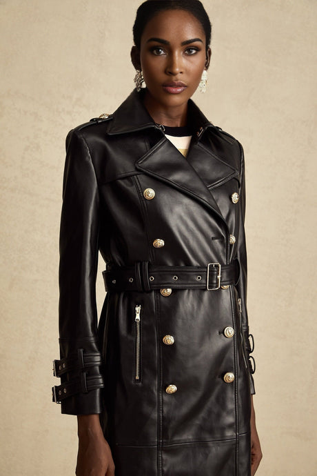 A black leather coat with doublebreasted front closure and belted waist featuring a long length and Camille style design