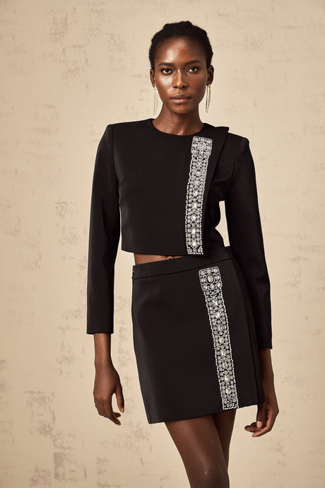 A black matching set consisting of a top and skirt adorned with crystal embellishments featuring the name Nadia