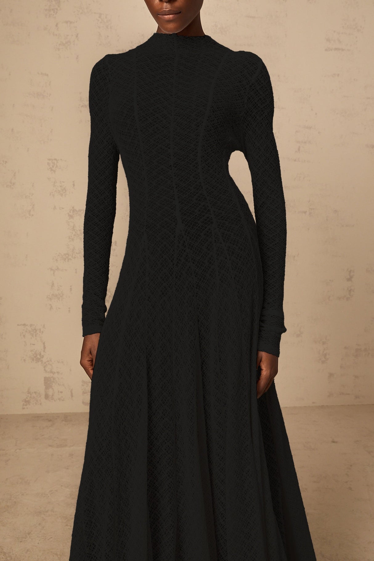 A black maxi dress with a wavy lace pattern featuring a long flowy silhouette and delicate lace detailing throughout
