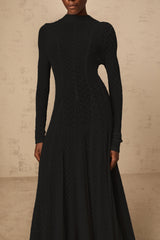 A black maxi dress with a wavy lace pattern featuring a long flowy silhouette and delicate lace detailing throughout