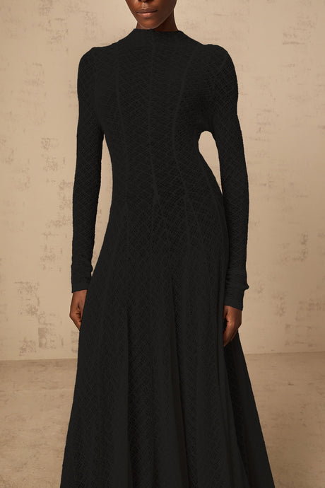 A black maxi dress with a wavy lace pattern featuring a long flowy silhouette and delicate lace detailing throughout