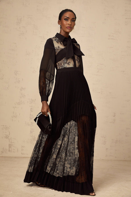 A black maxi dress with floral lace panels and pleated details named Segolene
