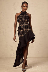 A black midi dress with an asymmetric hem featuring colorful floral appliques scattered across the fabric The dress has a fitted silhouette and likely includes a side slit for the asymmetric design