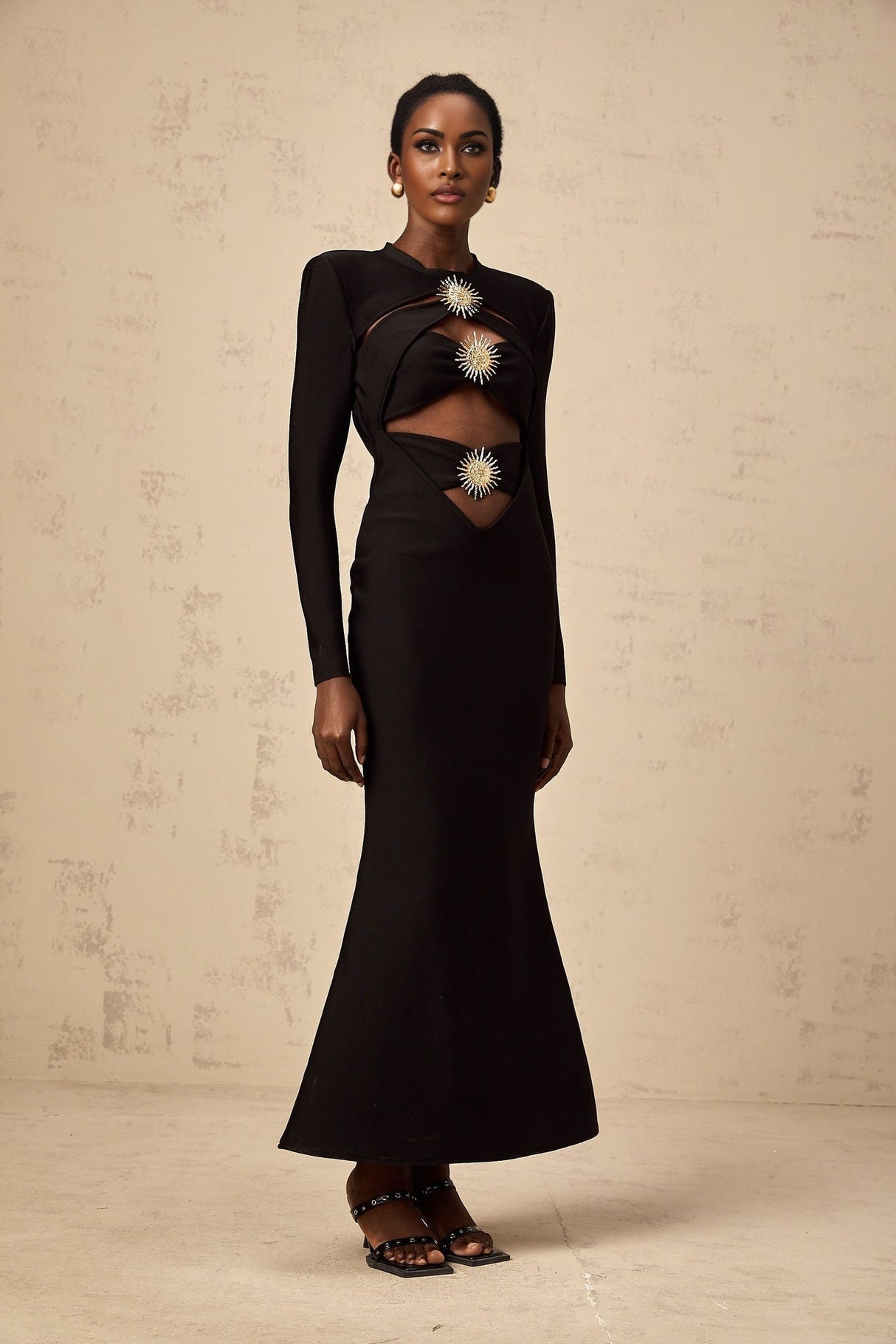 A black midi dress with cutout details featuring a sun motif design and ruched fabric Astrid collection