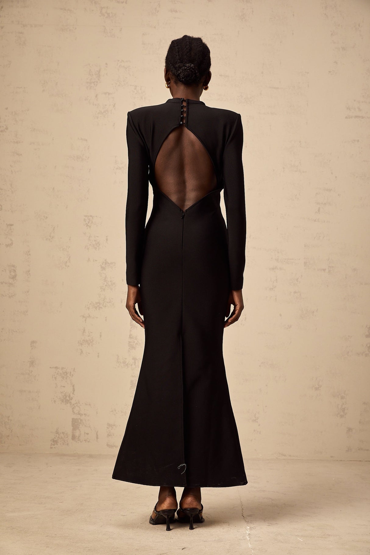 A black midi dress with cutout details featuring a sun motif pattern and ruched fabric Astrid style with a formfitting silhouette