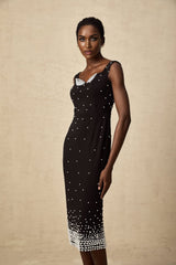 A black midi dress with faux pearl embellishments adorning the garment named Apolline