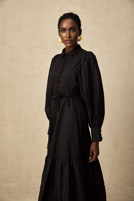 A black midi dress with lace embroidery details featuring a fitted silhouette and delicate floral patterns throughout the fabric