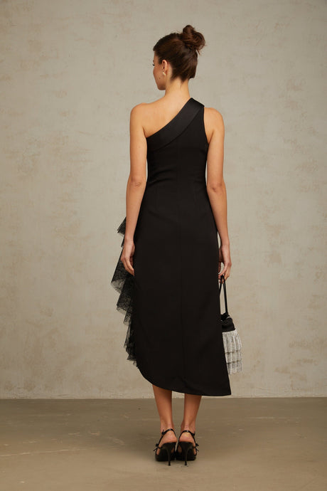 A black midi dress with lace panels and an asymmetric hemline worn by a model standing against a plain background