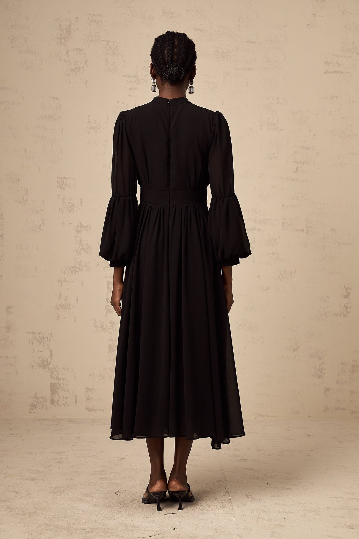 A black midi dress with pleated details and a buttonfront design called Viviane