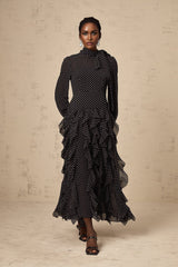 A black midi dress with white polka dots and ruffled details featuring a fitted bodice and flared skirt