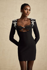 A black mini dress with a bustier top covered in shimmering sequins featuring thin straps and a short skirt