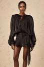 A black mini dress with a fully pleated design and ruffled details featuring a short hemline and feminine silhouette