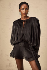 A black mini dress with a fully pleated design and ruffled details featuring a short length and feminine silhouette