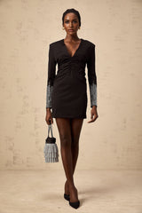 A black mini dress with a gathered design and rhinestone embellishments worn by a model named Suzy