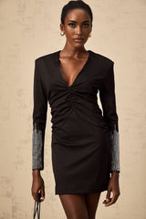 A black mini dress with a gathered design and rhinestone embellishments worn by a model