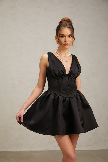 A black mini dress with a Vneck and flared skirt styled on a model