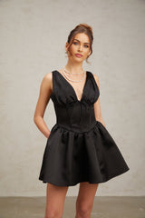 A black mini dress with a Vneck and flared skirt worn by a model standing against a plain background