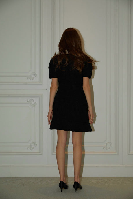 A black mini dress with a waffle knit texture featuring embellishments worn by a model named Ava