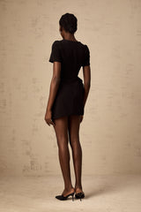 A black mini dress with an asymmetric design featuring ruffles and a short hemline