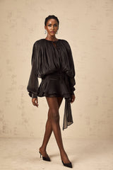 A black mini dress with full pleats and ruffled details featuring a short hemline and feminine silhouette