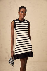 A black mini dress with horizontal stripes in a knit fabric worn by a model standing against a plain background