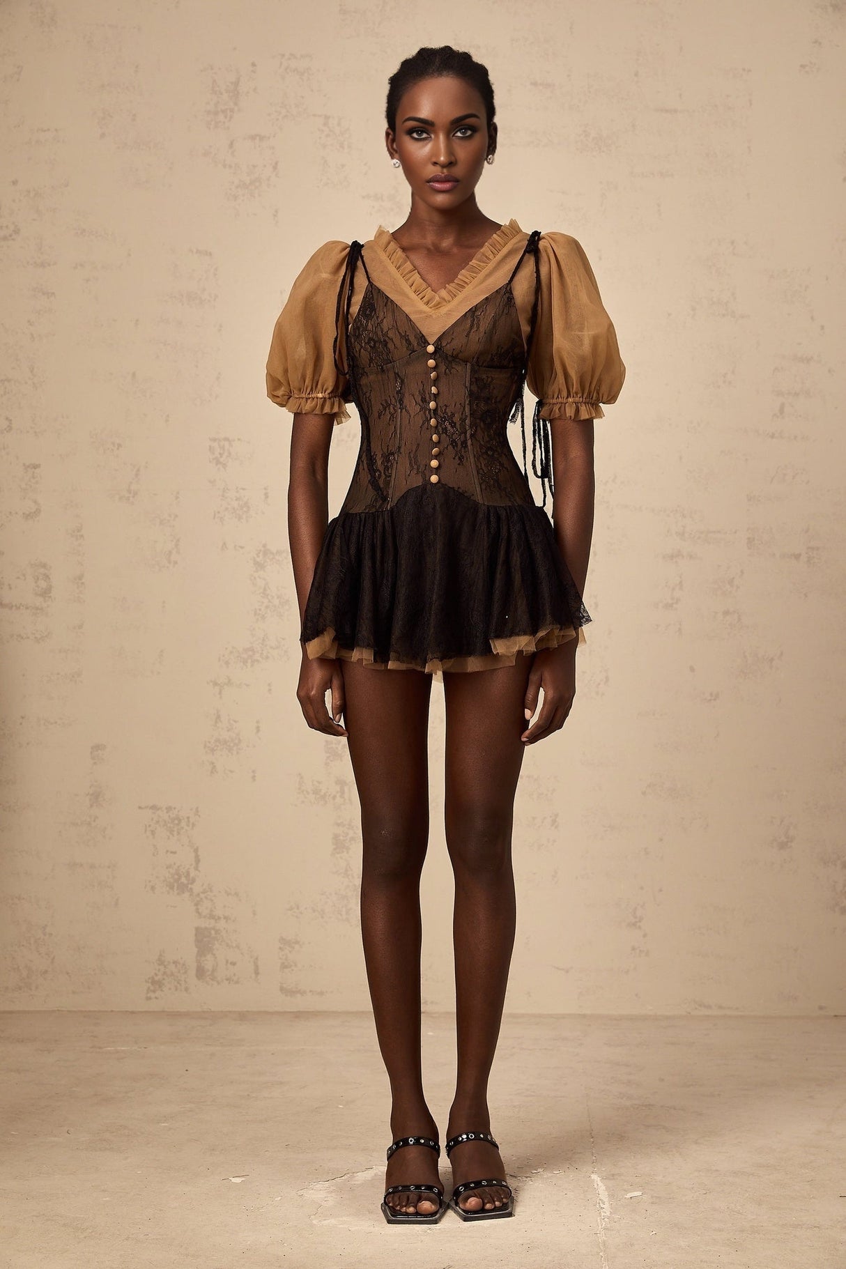 A black mini dress with lace panels featuring a fitted silhouette and delicate lace detailing throughout the bodice and sleeves