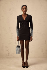 A black mini dress with rhinestone embellishments and gathered fabric detail worn by a model named Suzy