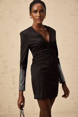A black mini dress with rhinestone embellishments and gathered fabric details worn by a model named Suzy