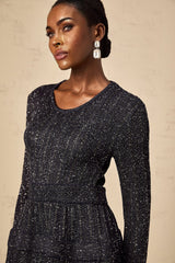A black mini dress with sequin embellishments and a knitted texture worn by a model named Alessandra