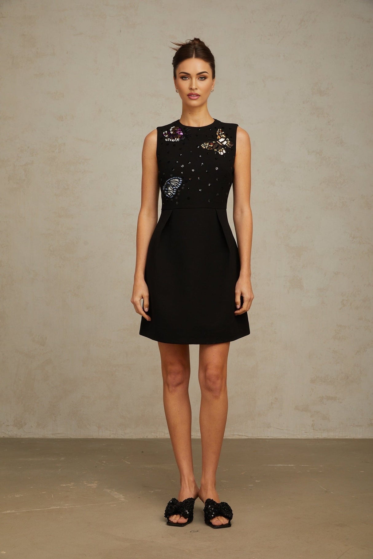 A black mini dress with sequin embellishments featuring a butterfly design Manon style short and fitted silhouette