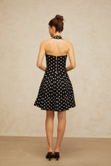 A black mini dress with white polka dots made of knit fabric featuring a fitted silhouette and short length