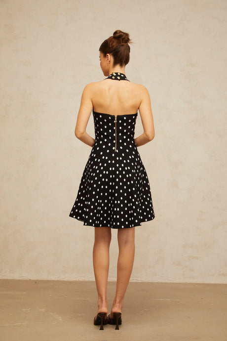 A black mini dress with white polka dots made of knit fabric featuring a fitted silhouette and short length