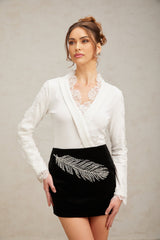 A black mini skirt with feather embroidery and embellishments featuring intricate detailing and a short hemline