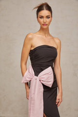 A black offshoulder maxi dress with a bow detail worn by a model against a plain background