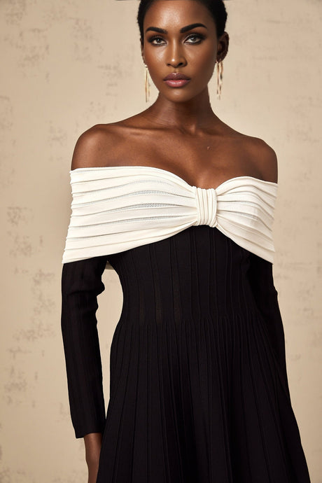A black offshoulder mini dress with a bow detail and knit texture worn by a model