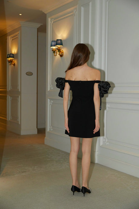 A black offshoulder mini dress with floral details named Erica worn by a model against a plain background