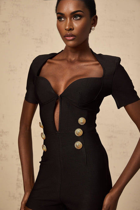 A black playsuit featuring embossed buttons named Solene worn by a model against a plain background