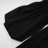A black pleated midi dress with a buttonfront design featuring long sleeves and a fitted waist