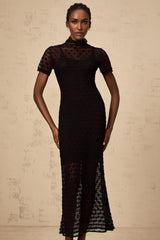 A black semi sheer knit midi dress on a mannequin or model showing the fitted silhouette and texture of the fabric