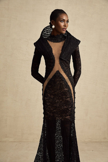 A black structured fishtail maxi dress with a split detail worn by a model standing against a plain background