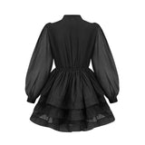 A black tiered flared mini dress with ruffled layers and short sleeves on a model against a plain background