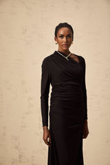 A black tulle maxi dress with asymmetric cut out details and an uneven hemline worn by a model against a plain background