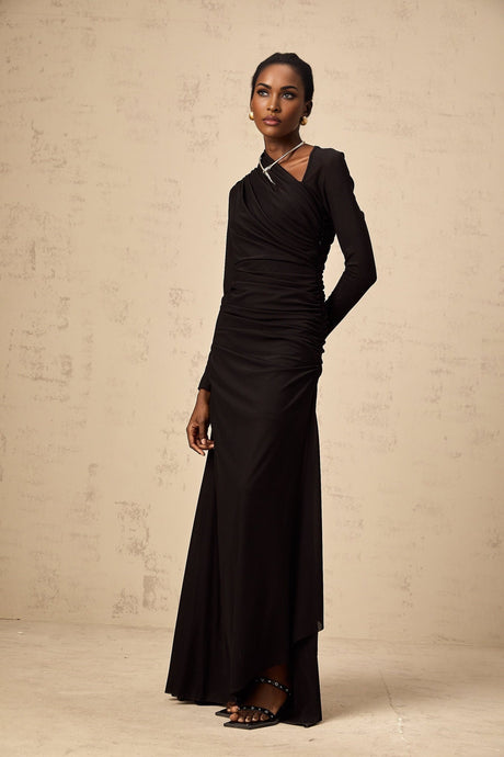 A black tulle maxi dress with asymmetric design and cutout details modeled by a woman