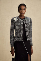 A black tweed jacket with a frayed edge design and a checkered pattern worn by a model named Justine