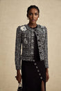 A black tweed jacket with a frayed edge design and a checkered pattern worn by a model named Justine