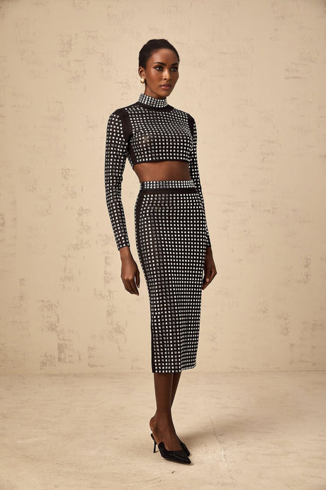 A black twopiece outfit consisting of a mesh top and skirt adorned with rhinestones featuring a matching design
