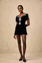 A black velvet mini dress with embellishments named Camille featuring a short hemline and decorative details