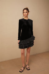 A black velvet mini dress with white polka dots featuring ruffled panels and a short hemline named Lucrezia
