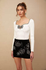 A black velvet mini skirt adorned with shimmering sequins creating a luxurious and glamorous look